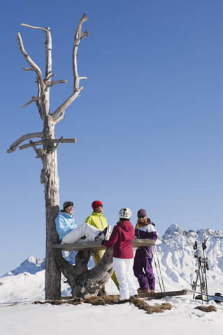 Italien, Trentino-Südtirol, Südtirol, Bozen, Seiser Alm, Menschen rasten bei kahlem Baum in verschneiter Landschaft, lizenzfreies Stockfoto