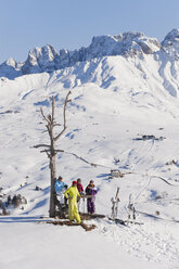 Italy, Trentino-Alto Adige, Alto Adige, Bolzano, Seiser Alm, People resting near bare tree on snowy landscape - MIRF000124