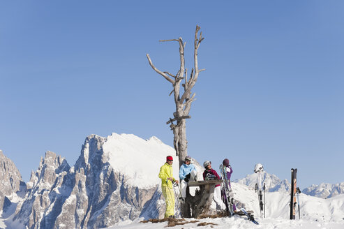 Italien, Trentino-Südtirol, Südtirol, Bozen, Seiser Alm, Menschen rasten bei kahlem Baum in verschneiter Landschaft - MIRF000125