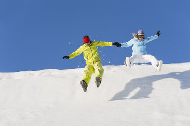 Italien, Trentino-Südtirol, Südtirol, Bozen, Seiser Alm, Mann und Frau springen auf Schnee - MIRF000187