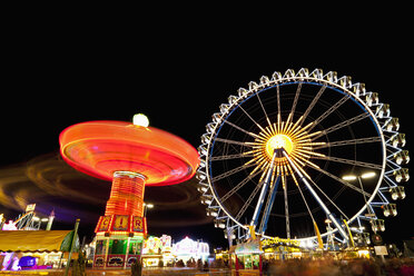 Deutschland, Bayern, München, Blick auf beleuchtetes Kettenkarussell und Riesenrad bei Nacht - FOF003337