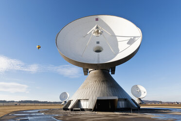 Deutschland, Bayern, Raisting, Blick auf Antennen einer Bodenstation mit Heißluftballon in der Ferne - FOF003358