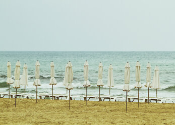 Spanien, Alicante, Blick auf leeren Strand mit aufgespannten Sonnenschirmen und Liegestühlen - MBEF000087