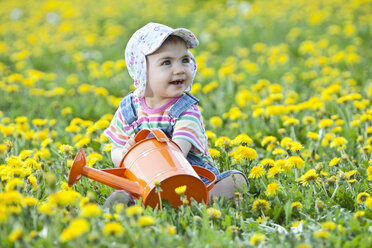 Deutschland, Bayern, Baby-Mädchen hält Gießkanne in Blumenfeld, lächelnd - MAEF003243