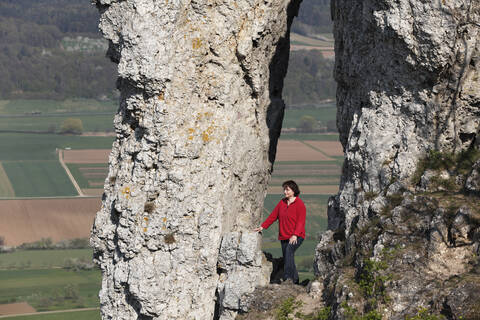 Deutschland, Bayern, Franken, Fränkische Schweiz, Walberla, Blick auf reife Frau beim Wandern in der Nähe von Felsformationen am Berg, lizenzfreies Stockfoto
