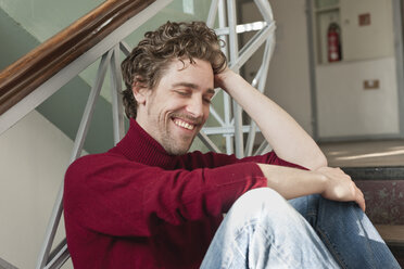 Mid adult man sitting on stairway, smiling - DBF000084