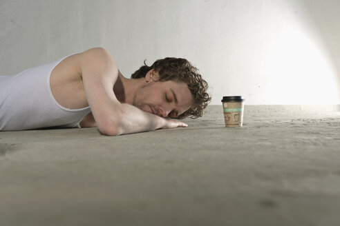 Mittlerer erwachsener Mann auf dem Boden liegend mit Kaffeetasse daneben - DBF000096