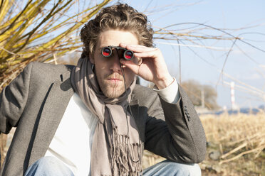 Germany, Hamburg, Man looking through binoculars near Elbe riverside - DBF000124