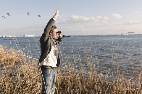 Germany, Hamburg, Man looking through binoculars near Elbe riverside stock photo