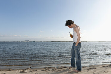 Germany, Hamburg, Man with beer bottle near Elbe riverside - DBF000129