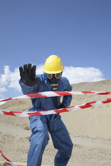 Deutschland, Bayern, Mann in Schutzkleidung bei Sanddüne und Absperrband im Vordergrund - MAEF003302