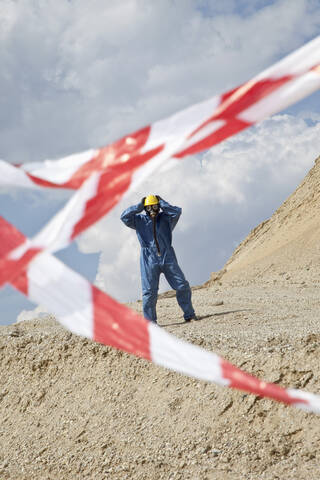 Deutschland, Bayern, Mann in Schutzkleidung auf Sanddüne und Absperrband im Vordergrund, lizenzfreies Stockfoto