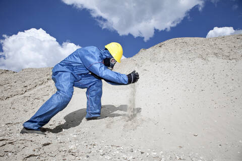 Deutschland, Bayern, Mann in Schutzkleidung verschüttet Sand auf Sanddüne, lizenzfreies Stockfoto