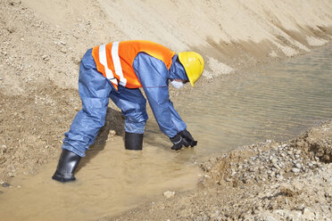 Deutschland, Bayern, Mann in Arbeitsschutzkleidung bei der Suche in einem Wasserlauf - MAEF003317