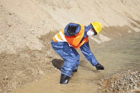 Deutschland, Bayern, Mann in Arbeitsschutzkleidung bei der Suche in einem Wasserlauf - MAEF003318