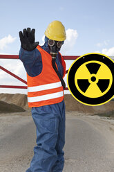 Deutschland, Mann in Arbeitsschutzkleidung in der Nähe eines radioaktiven Warnsymbols - MAEF003321