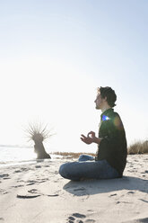 Germany, Hamburg, Mid adult man doing yoga near Elbe river - DBF000072