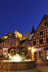 Germany, Bavaria, Franconia, Upper Franconia, Franconian Switzerland, Pottenstein, Osterbrunnen, View of town with easter decoration on fountain at night - SIEF001482