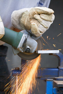 Close up of man cutting piece of iron with angle grinder - TSF000259