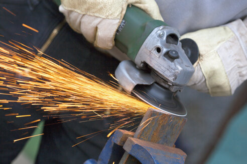 Close up of man sharpening piece of iron with angle grinder - TSF000258