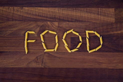 Close up of word food written with penne on wooden background - TSF000255