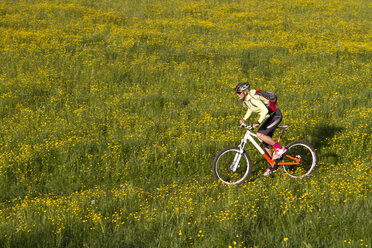 Deutschland, Bayern, Schliersee, Frau beim Mountainbiken im Feld - FFF001156