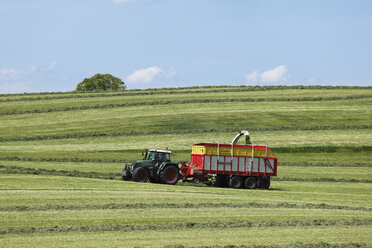 Deutschland, Bayern, Oberbayern, Münsingen, Blick auf eine Mähwiese mit Traktor im Frühling - SIEF001559