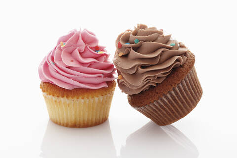 Nahaufnahme von Erdbeere und Schokolade Buttercreme Cupcakes gegen weißen Hintergrund, lizenzfreies Stockfoto