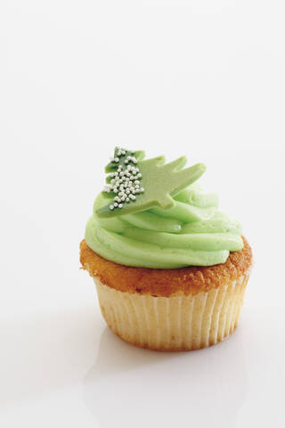 Nahaufnahme von Waldmeister Buttercreme Cupcake mit Weihnachten Aufkleber gegen weißen Hintergrund, lizenzfreies Stockfoto