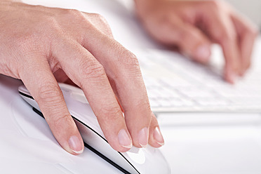 Close up of woman's hand holding mouse and writing on keyboard - TSF000249