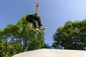 Deutschland, Düsseldorf, Junger Mann macht Tricks mit Skateboard im Skatepark - KJF000106