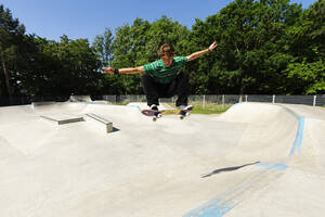 Deutschland, Düsseldorf, Junger Mann macht Tricks mit Skateboard im Skatepark - KJF000105