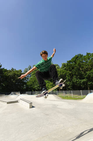 Germany, Duesseldorf, Young man performing tricks with skateboard in skatepark stock photo