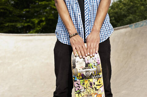 Germany, NRW, Duesseldorf, Man holding skateboard at public skatepark stock photo