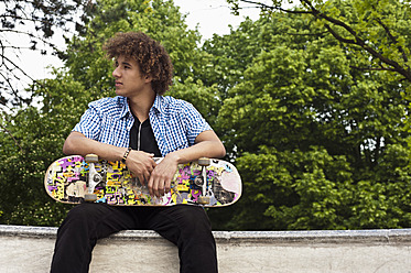 Deutschland, NRW, Düsseldorf, Mann hält Skateboard in öffentlichem Skatepark - KJF000112