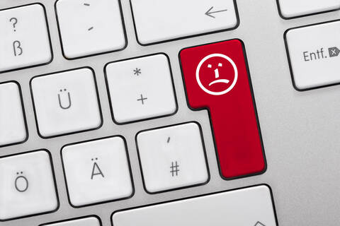 Illustration einer Tastatur mit roter Taste und traurigem Gesicht, Nahaufnahme, lizenzfreies Stockfoto