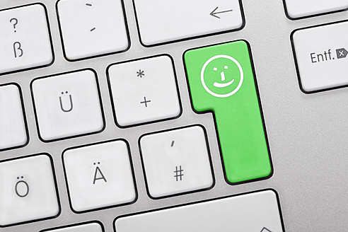 Illustration of keyboard having green key with smiley face, close up - TSF000303