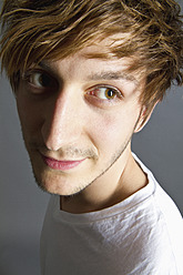 Close up of young man against grey background, smiling - MBEF000122