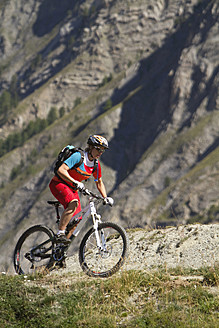 Italien, Livigno, Blick auf eine Frau, die in der Nähe eines Berges Mountainbike fährt - FFF001171