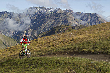 Italien, Livigno, Blick auf eine Frau, die mit dem Mountainbike bergauf fährt - FFF001173