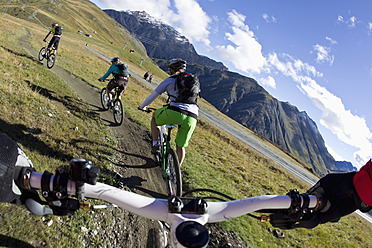 Italien, Livigno, Blick auf Frau und Mann beim Mountainbikefahren bergab - FFF001174