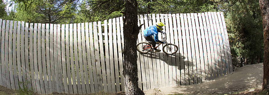 Italy, Livigno, View of man wall riding mountain bike at bikepark - FFF001176