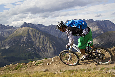 Italy, Livigno, View of man riding mountain bike downhill - FFF001192