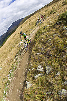 Italien, Livigno, Blick auf Frau und Mann beim Mountainbikefahren bergab - FFF001195