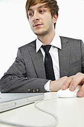 Young businessman working on laptop against white background, close up - MBEF000141