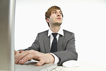 Young businessman working on laptop against white background - MBEF000143