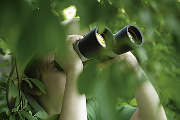 Germany, Bavaria, Close up of boy looking through binocular in forest - TCF001547