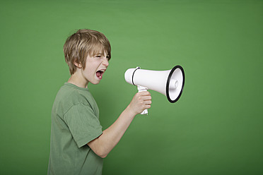 Junge schreit in Megaphon gegen grünen Hintergrund - TCF001552