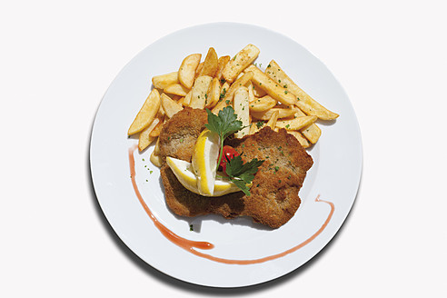 Nahaufnahme von Wiener Schnitzel mit Pommes frites vor weißem Hintergrund - CSF015132