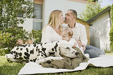 Germany, Bavaria, Father, mother and daughter with dalmatian in garden, smiling - RNF000619